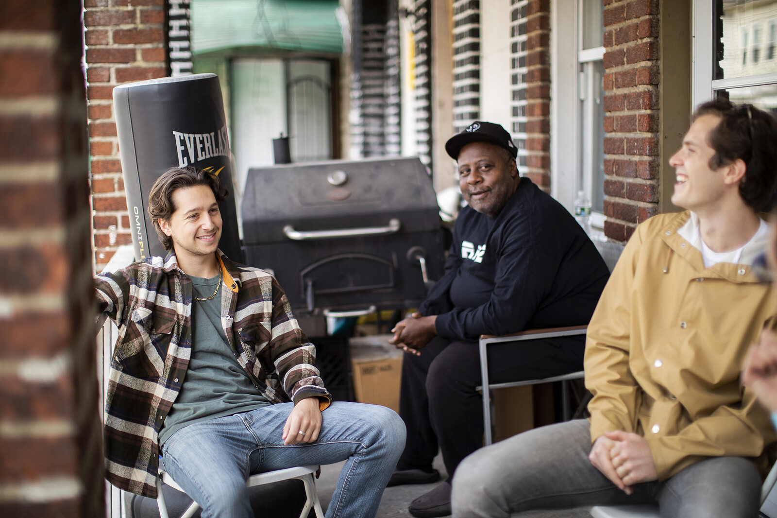 Community Grocer founders Eli Moraru and Alexandre Imbot sitting on a West Philly porch with community activist Charles Reeves